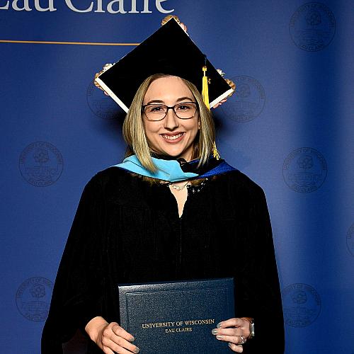 Female graduate in cap and gown, blond, glasses. Courtney Stearns