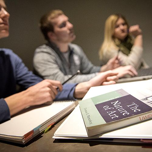 A picture of three students studying and the "The Nature of Art" on the table